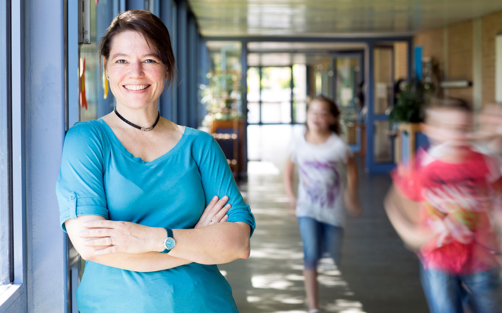 Smiling educator standing in hall as students walk past