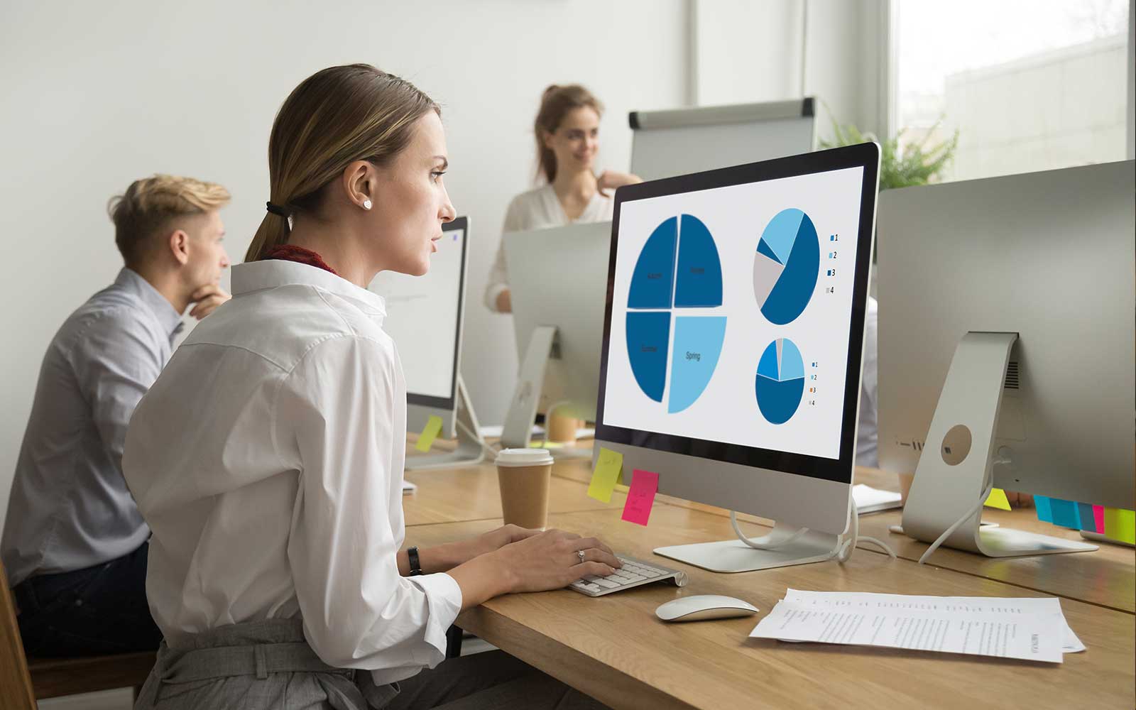 Woman at desk analyzing data on computer