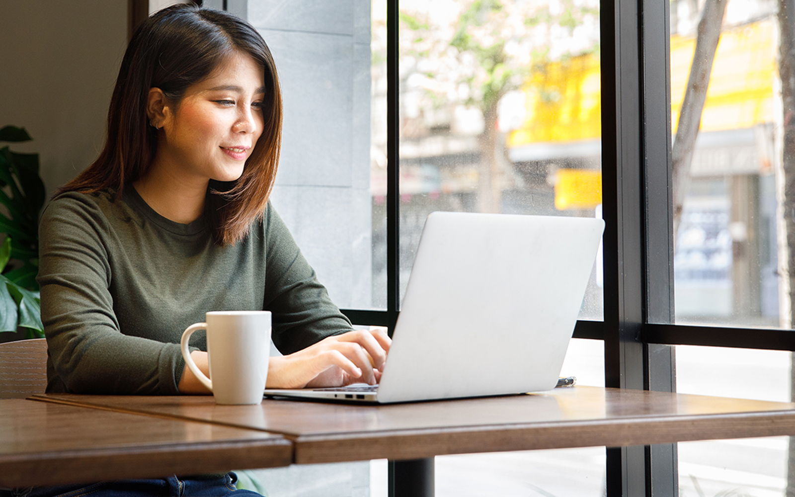 Woman working on her online MPA coursework on a laptop at a coffee shop