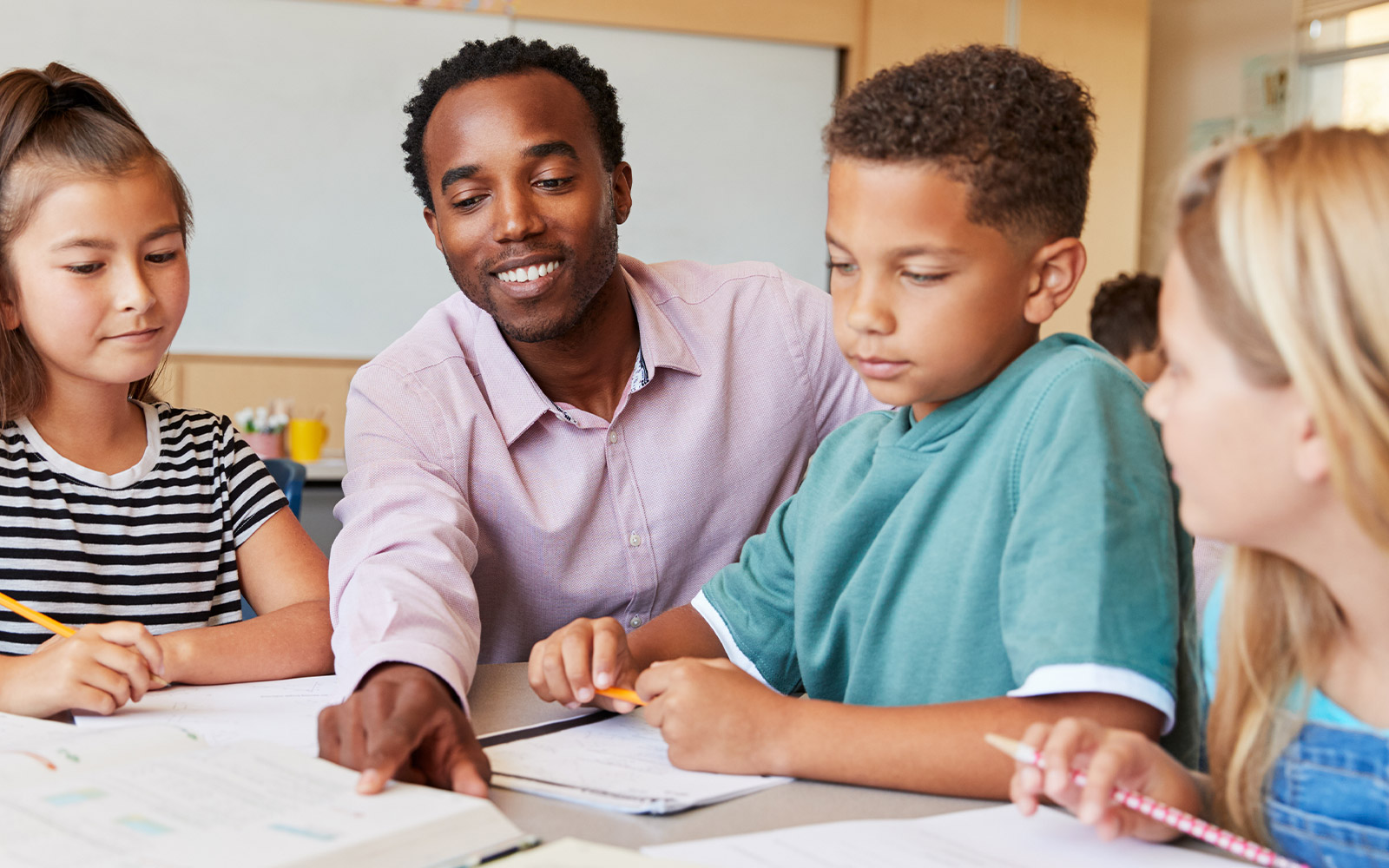 Teacher showing students something on desk