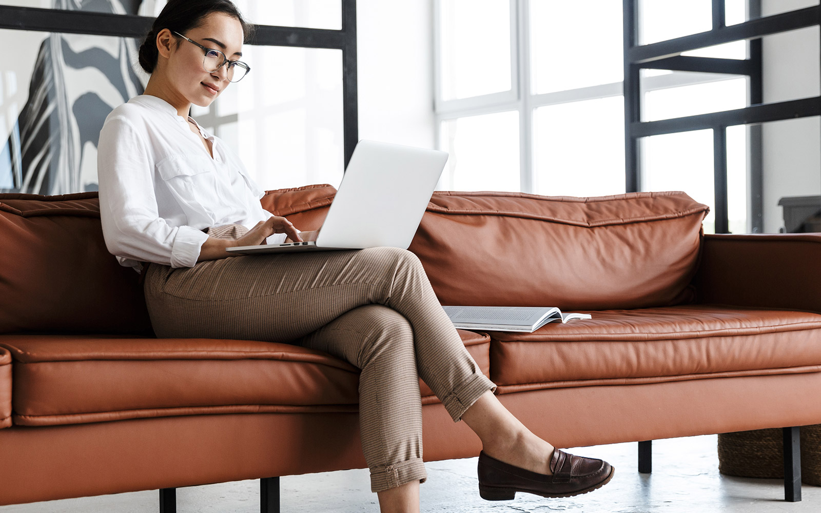 Woman sitting on a couch looking at her laptop