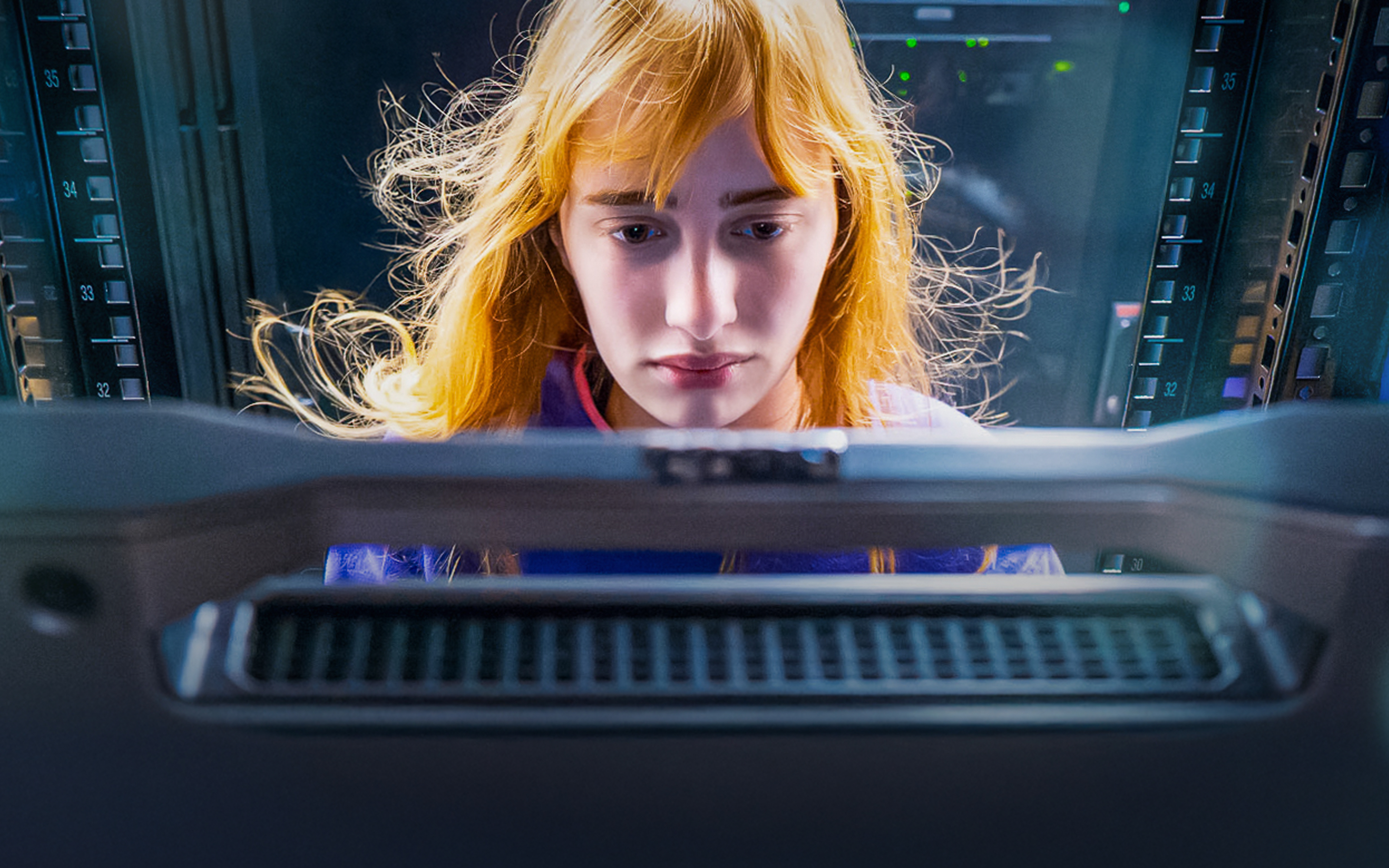 Young woman looking at a computer screen in a server room.