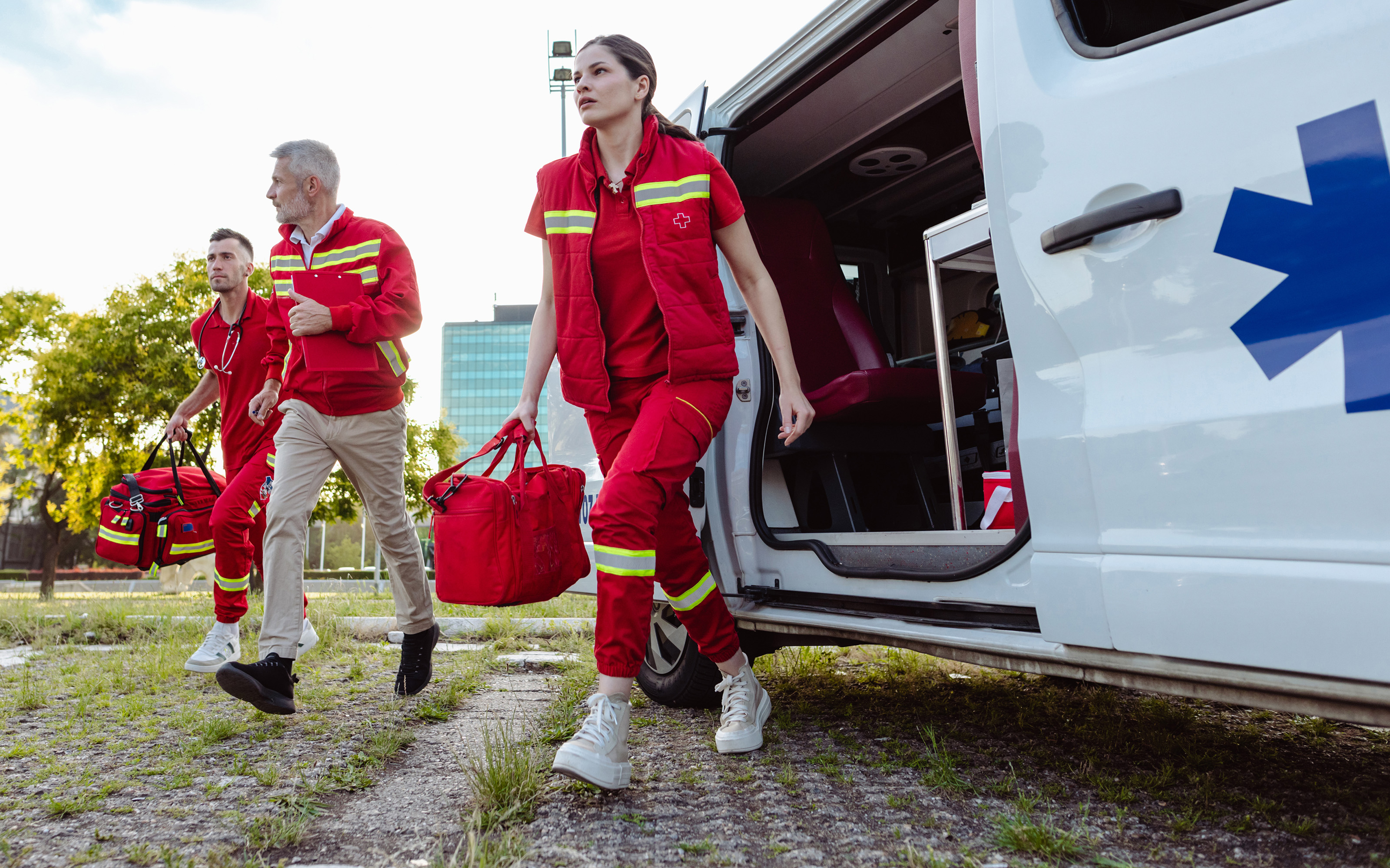 Group of emergency management professionals wearing orange safety vests discussing a response plan inside an industrial facility.