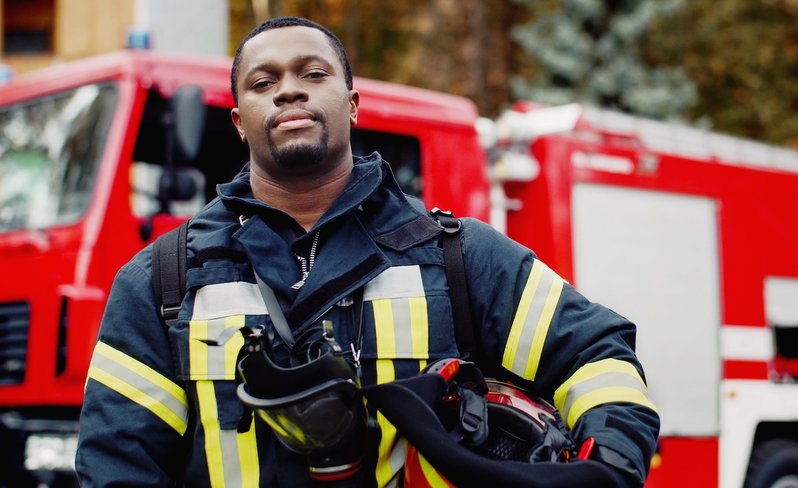 Fireman smiling at camera holding his helmet at the side.