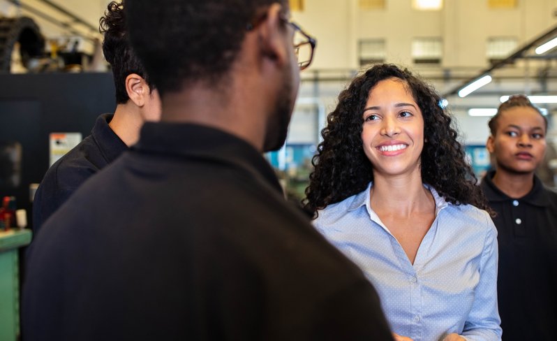 Female supervisor talking with group of workers in a factory.
