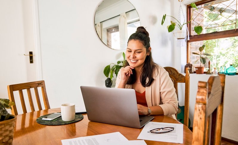 Young Latina woman using her laptop at dining table.