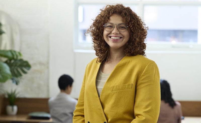 Young professional woman in the office with a yellow casual blazer.
