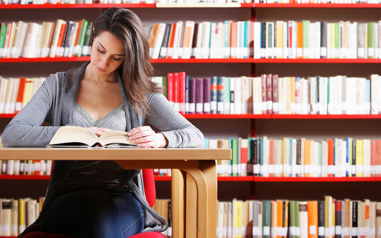 English student reading textbook in library.
