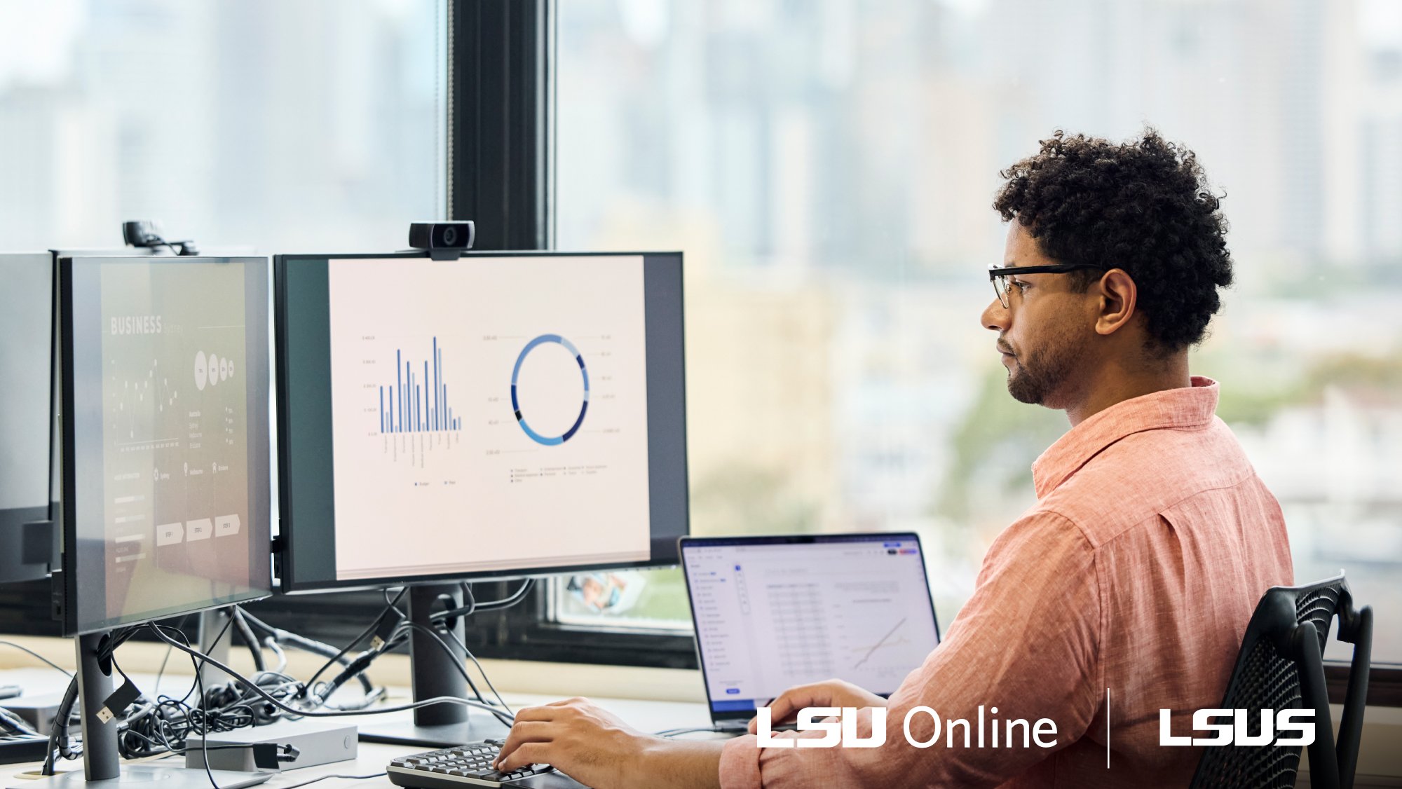 Man working in finance sitting at desk reviewing graphs and charts on computer monitors.
