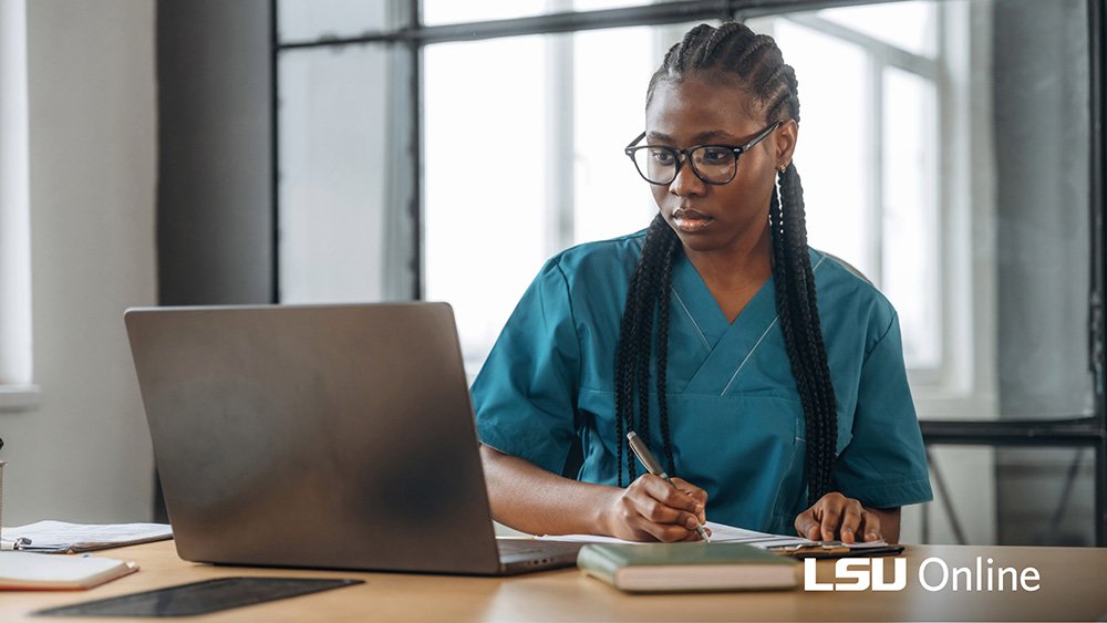 Healthcare worker taking notes at laptop