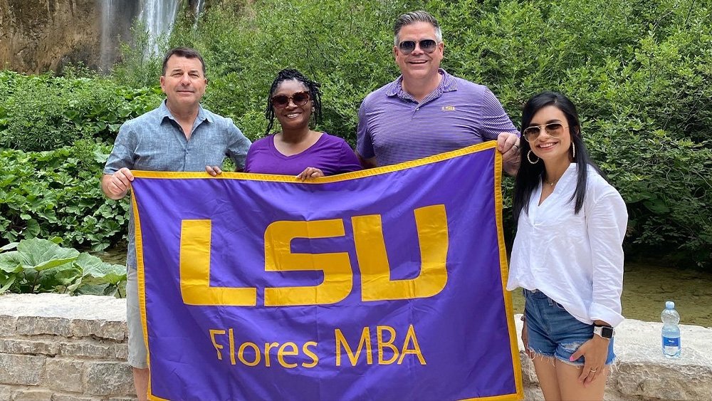 LSU Online MBA faculty with MBA flag while abroad