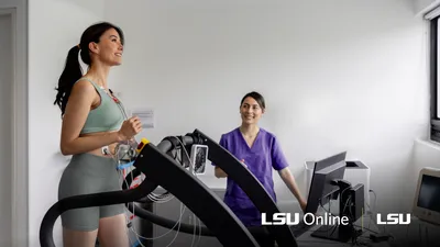 Woman running on treadmill while athletic trainer takes notes in background