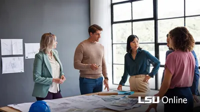 Facility manager speaking with other construction professionals around a table with plans.