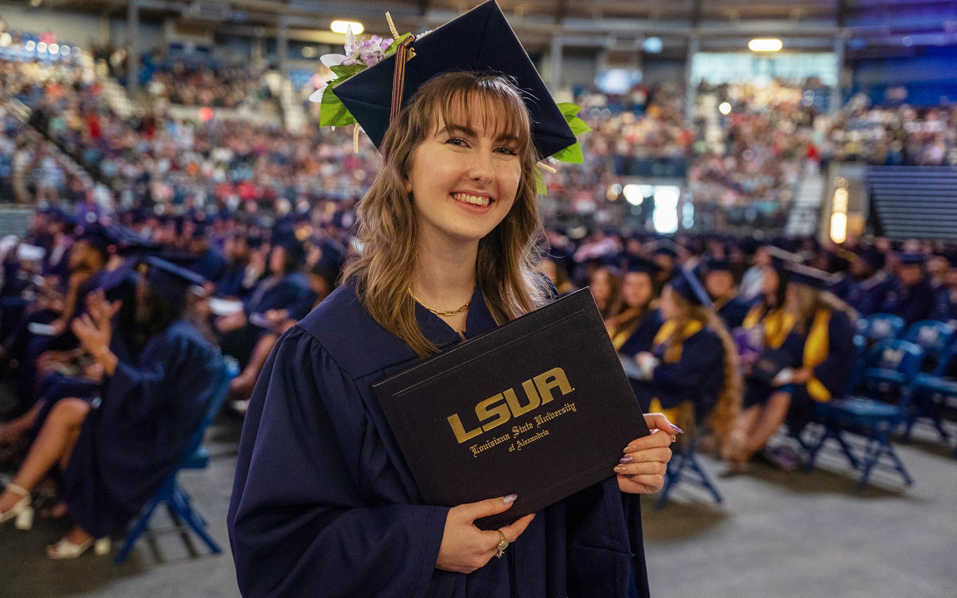 LSUA Graduate smiling at camera holding her degree.