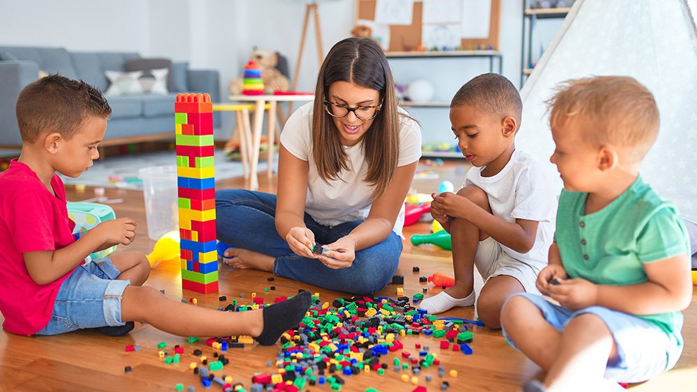 Early childhood instructor playing Legos with children