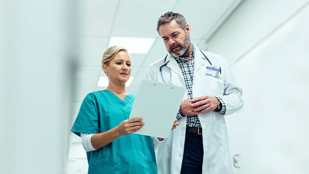 Nurse and doctor talking in a medical facility hallway