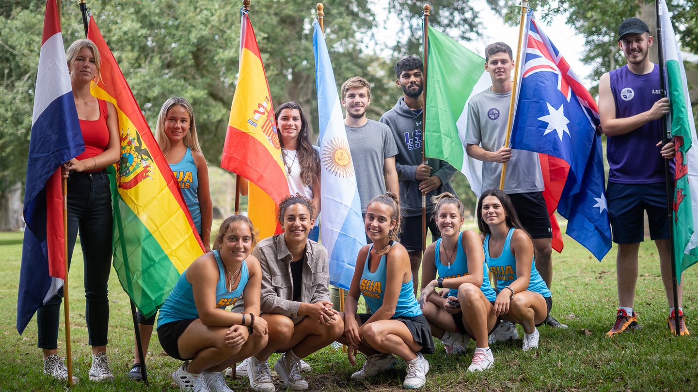 Diverse group of students holding flags from different countries.