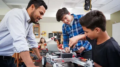 Teacher instructing two students at desk
