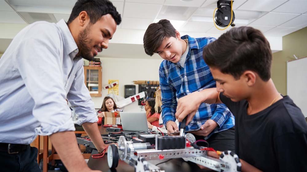 Teacher instructing two students at desk