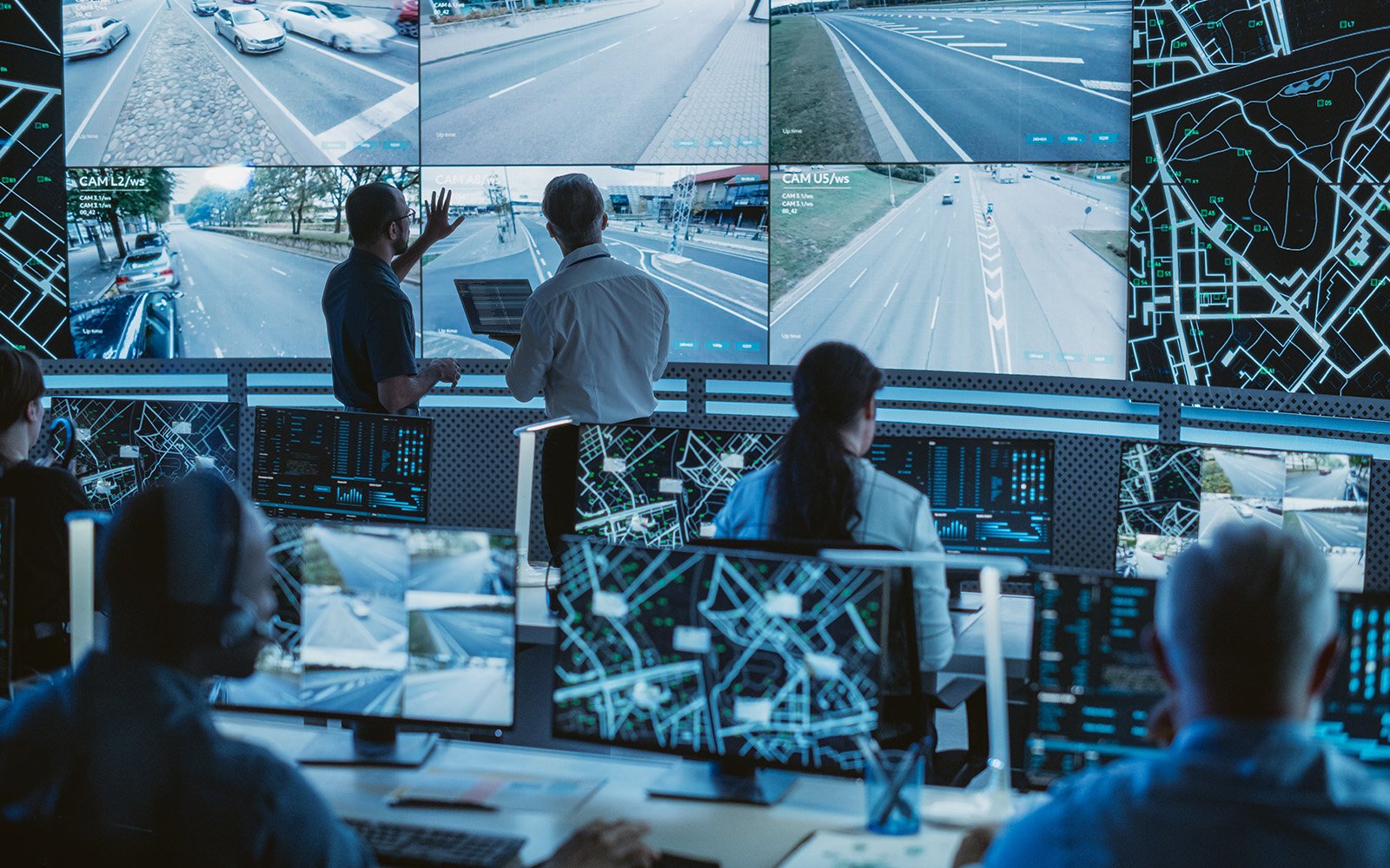 A control room with people monitoring surveillance screens.