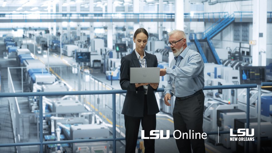 Engineering manager reviewing work on laptop inside a factory