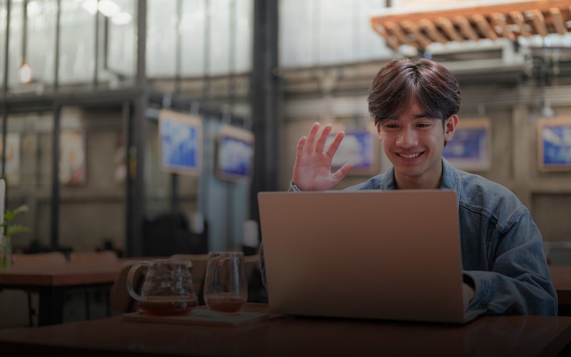 Young male student waving hi on a video call.