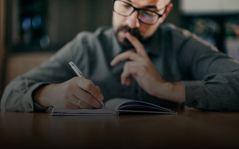 Man thinking and writing down notes at home.