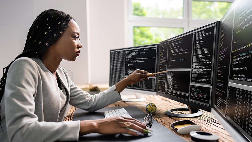Woman working at desk with computers.