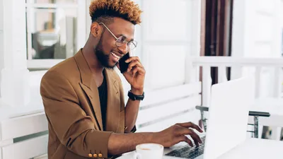 Salesperson talking to marketing department on phone in front of laptop