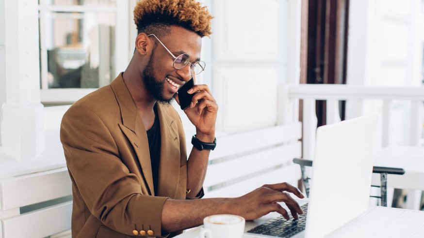 Salesperson talking to marketing department on phone in front of laptop