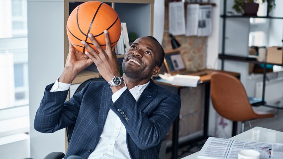 Sports manager handles basketball while sitting at his desk.