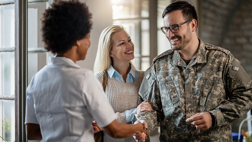 Military personnel shaking hands with a woman while smiling