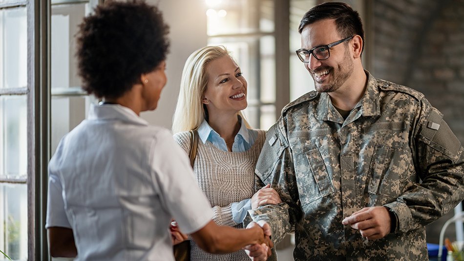 Military personnel shaking hands with a woman while smiling