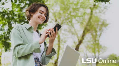 A woman with short brown hair smiles down at her cell phone.