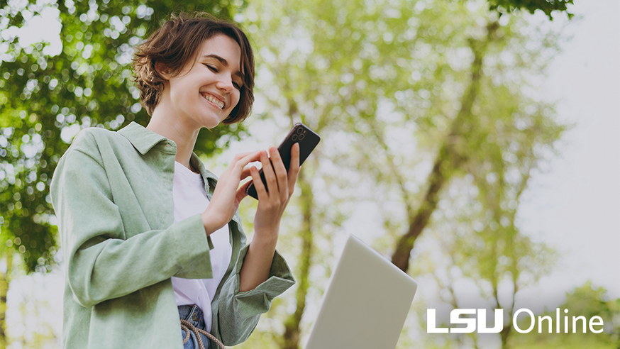 A woman with short brown hair smiles down at her cell phone.