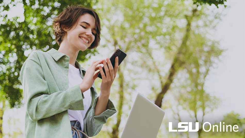A woman with short brown hair smiles down at her cell phone.
