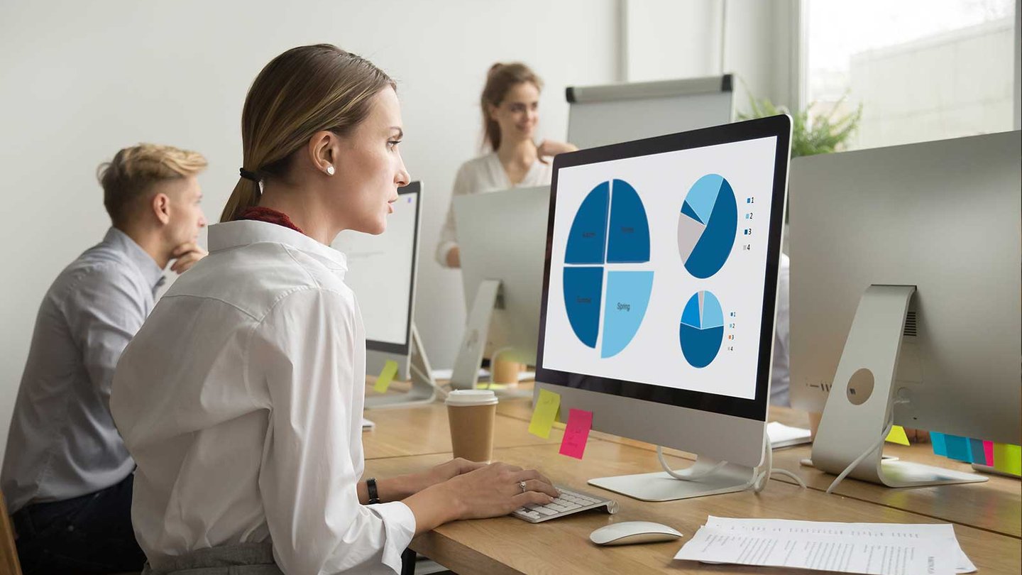Woman at desk analyzing data on computer