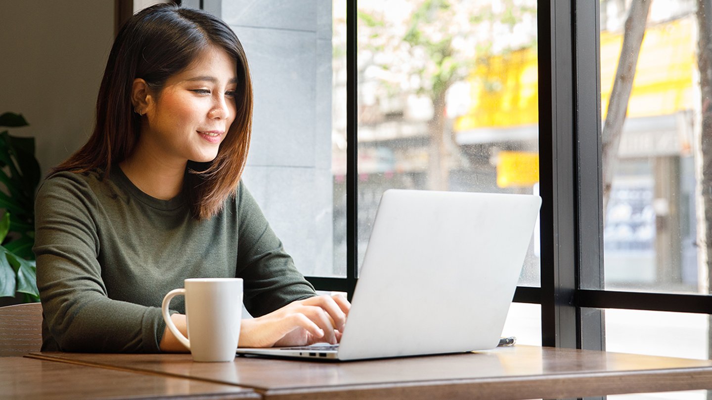 Woman working on her online MPA coursework on a laptop at a coffee shop