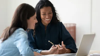 Two women smiling at a laptop