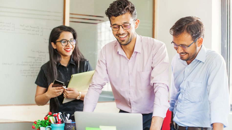 Group of employees smiling around a laptop