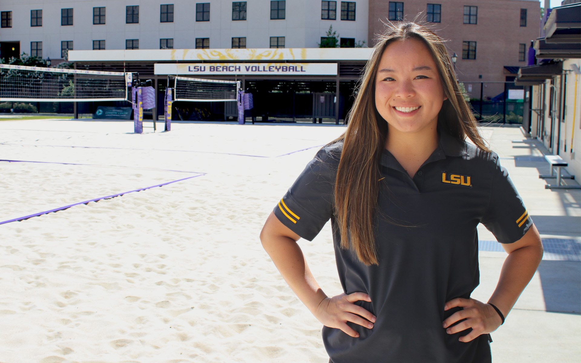 LSU sports program student standing in front of outdoor sand volleyball courts