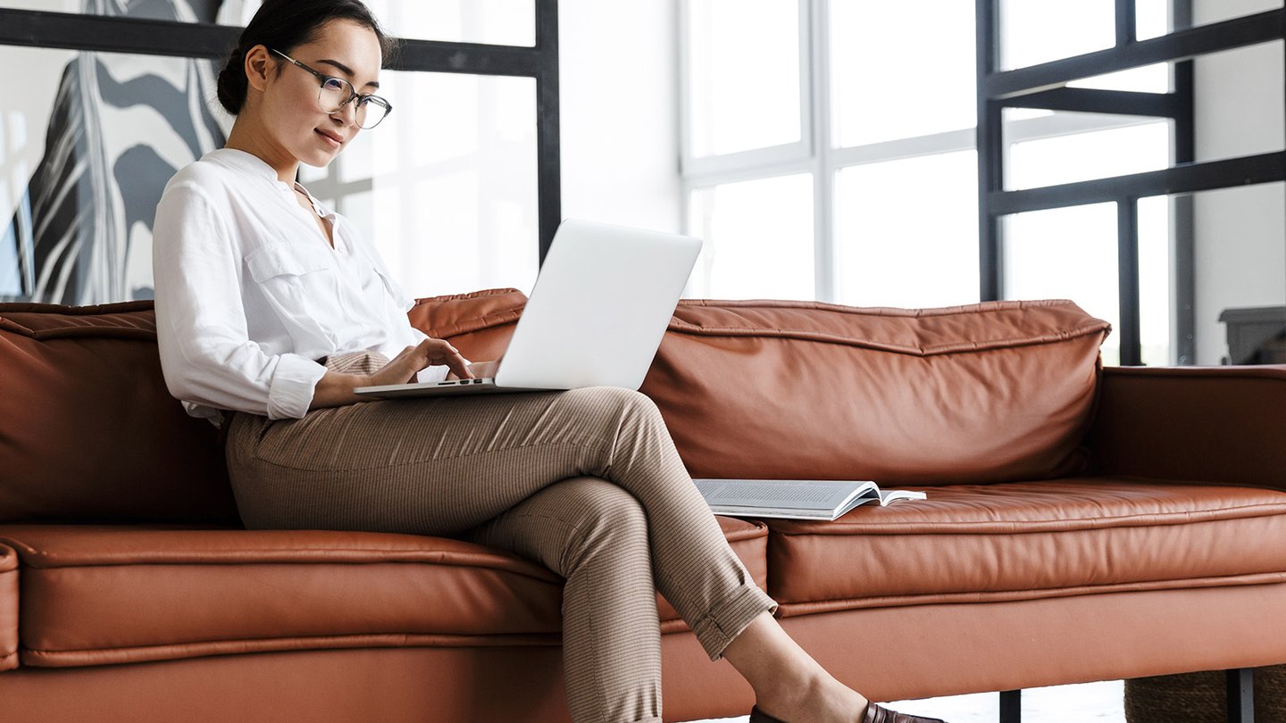 Woman sitting on a couch looking at her laptop