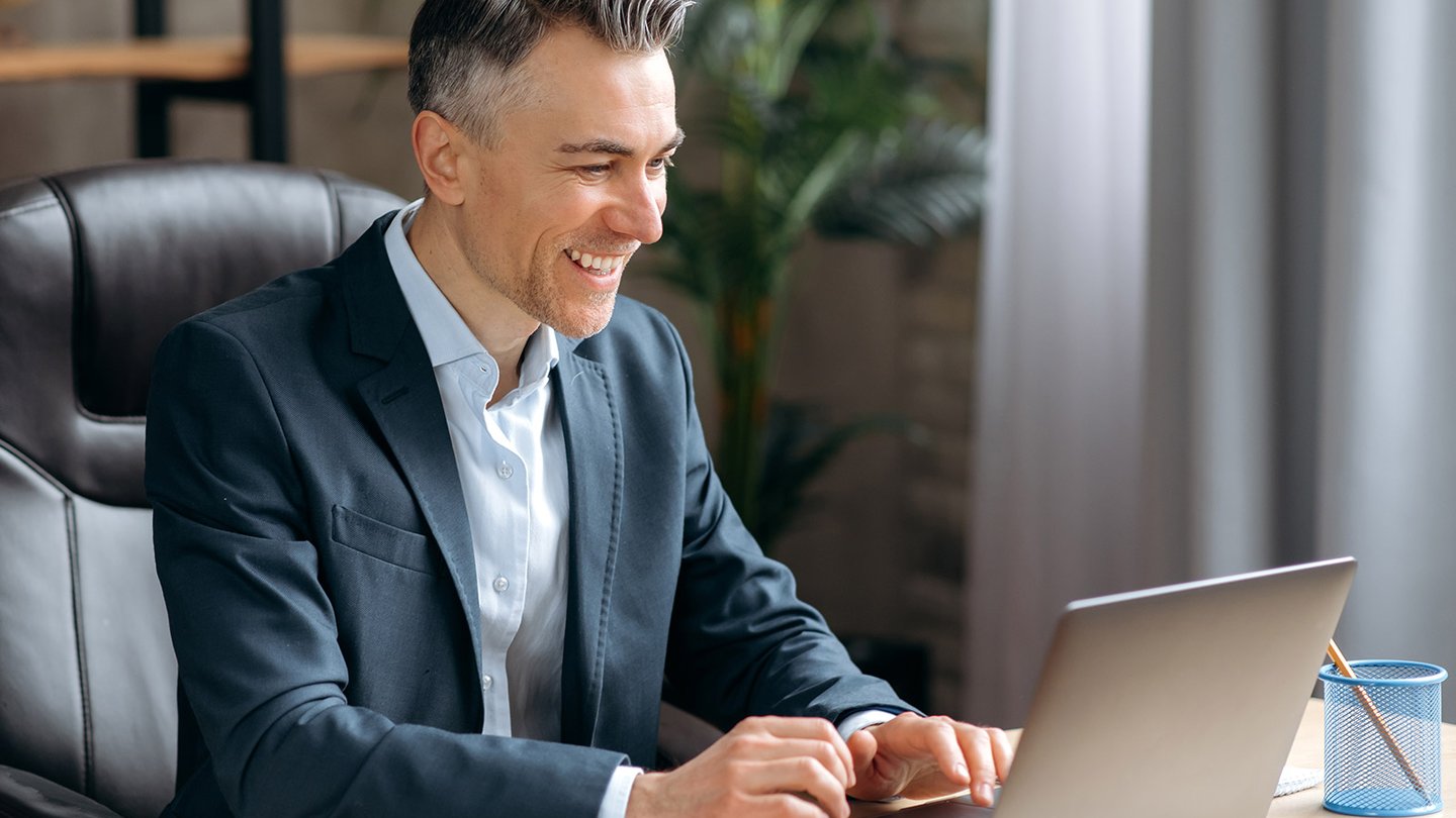 Professional man typing on laptop at desk in office
