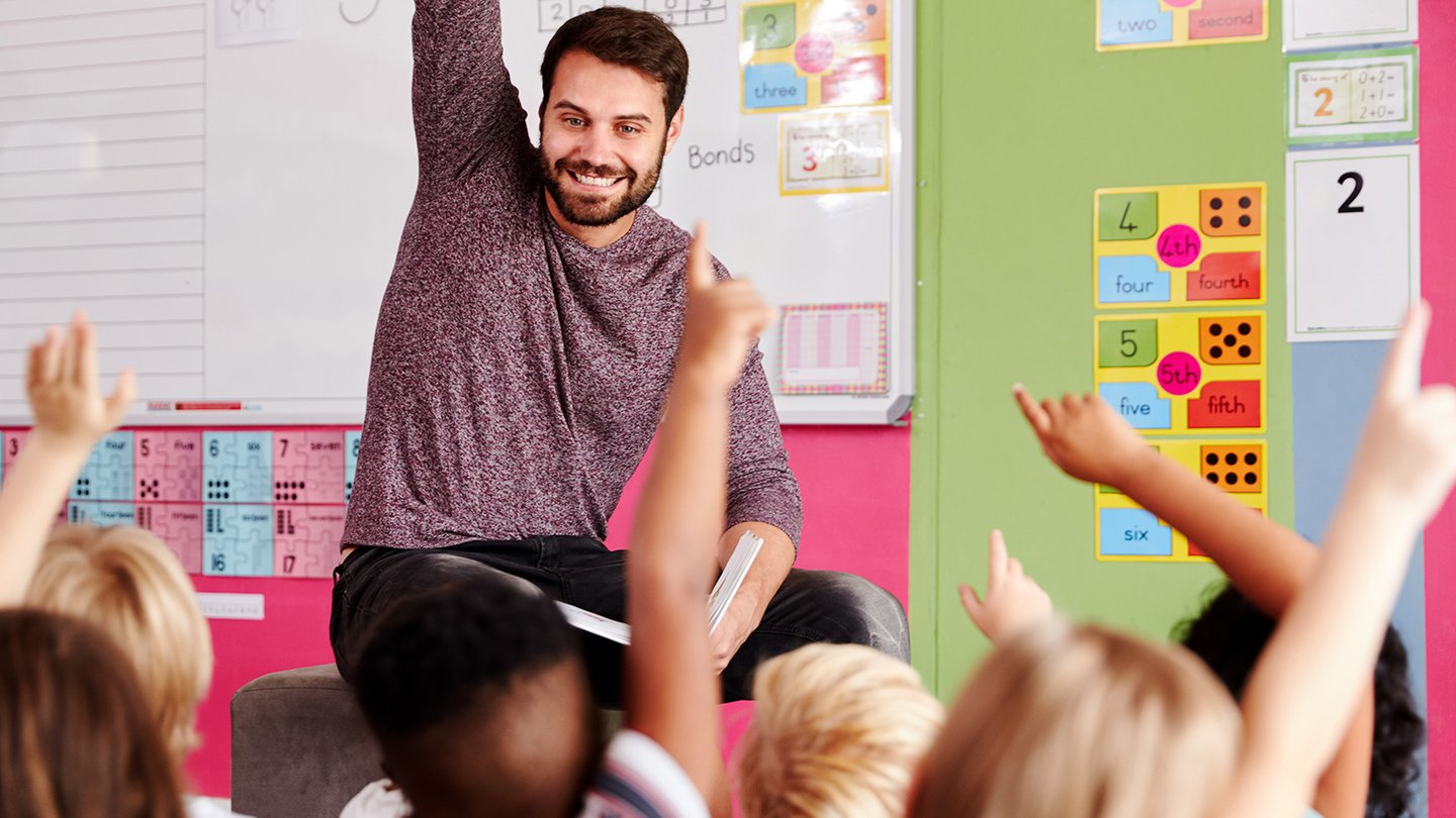 Teacher raising his hand in front of class