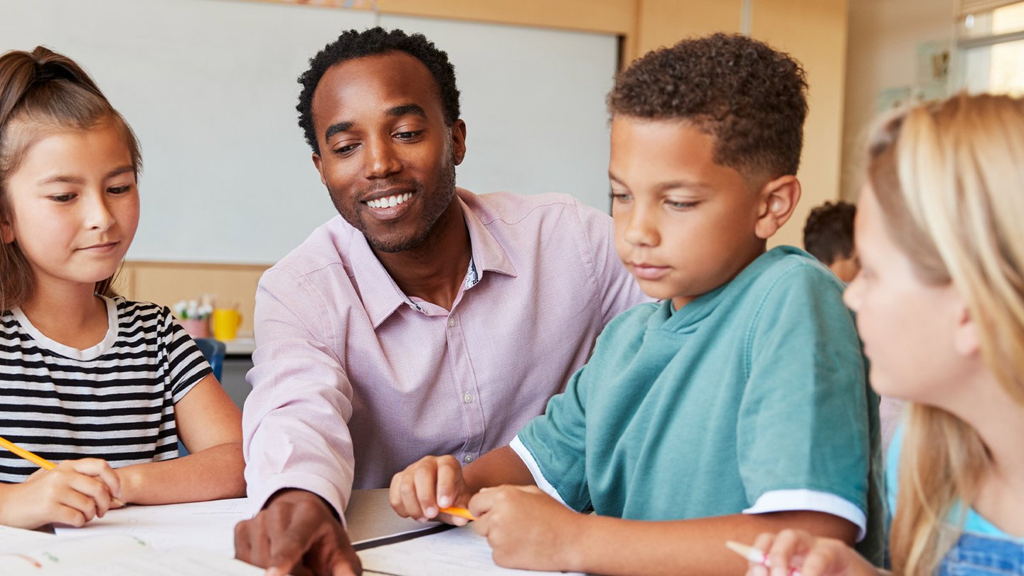 Teacher showing students something on desk