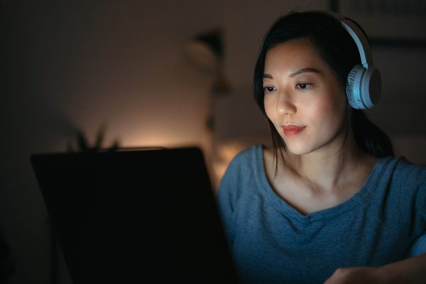 Female tech student working on laptop with headphones on.