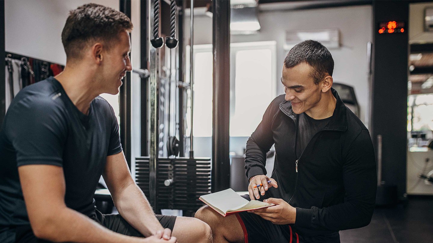 Coach/trainer working with client in weight room