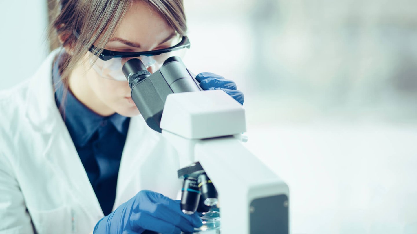 Scientist looking through microscope in lab