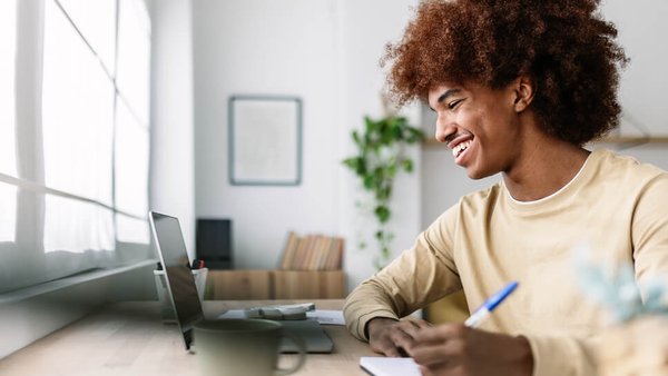 Man taking notes by laptop