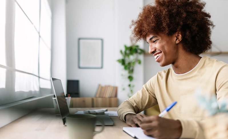Man taking notes by laptop